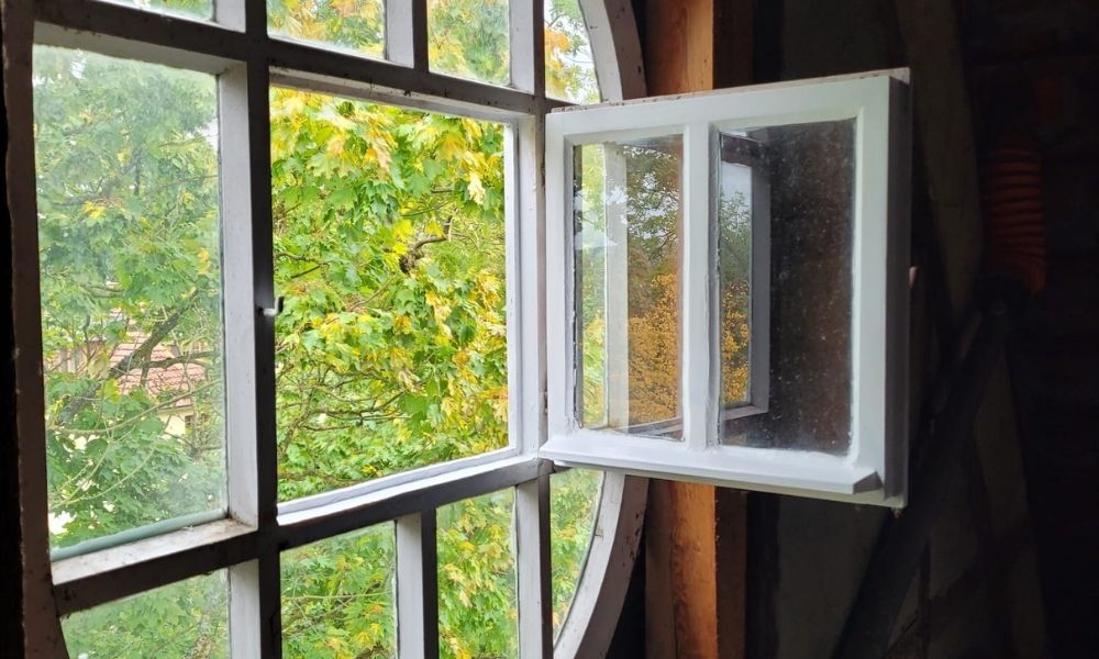 Kreisrundes, repariertes Fenster mit Sprossen im Denkmalschutz